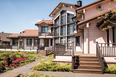Modelo de fachada de casa rosa tradicional grande de tres plantas con revestimiento de madera