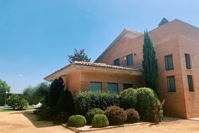 Modelo de fachada de casa marrón y marrón contemporánea grande de dos plantas con revestimiento de ladrillo, tejado a doble faldón y tejado de teja de barro