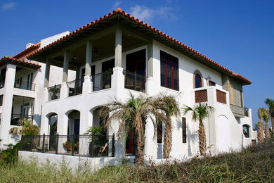 Imagen de fachada de casa blanca mediterránea de tamaño medio de dos plantas con revestimiento de estuco, tejado a cuatro aguas y tejado de teja de barro