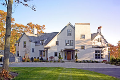 Cette photo montre une grande façade de maison beige bord de mer en stuc à deux étages et plus avec un toit à deux pans.