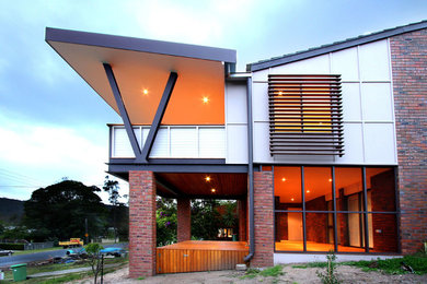 Imagen de fachada beige moderna de tamaño medio de dos plantas con revestimiento de aglomerado de cemento y tejado plano