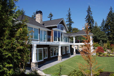 Diseño de fachada de casa marrón costera grande de dos plantas con revestimiento de madera, tejado a cuatro aguas y tejado de teja de madera