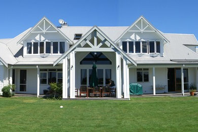 Diseño de fachada blanca clásica grande de dos plantas con revestimiento de madera y tejado a dos aguas