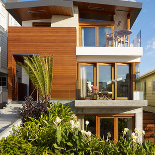 Foto della facciata di una casa unifamiliare tropicale a tre piani di medie dimensioni con rivestimento in legno e copertura in metallo o lamiera