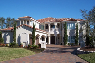 Example of a large tuscan black two-story stucco exterior home design in Jacksonville with a hip roof