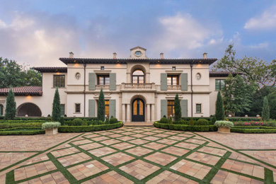 Example of a huge tuscan beige two-story stucco house exterior design in Dallas with a hip roof and a tile roof