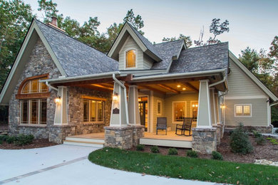 Modelo de fachada de casa beige de estilo americano grande de tres plantas con revestimiento de piedra, tejado a dos aguas y tejado de teja de madera