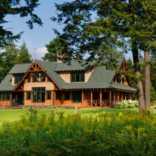 Inspiration pour une très grand façade de maison marron chalet à un étage avec un toit à croupette et un toit végétal.