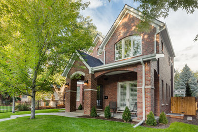 Traditional red two-story brick exterior home idea in Denver with a shingle roof