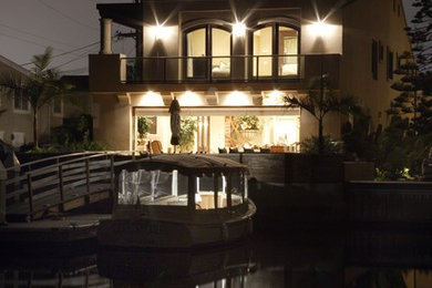 Example of a large beach style beige three-story stucco exterior home design in Orange County