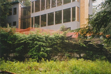 Foto de fachada moderna de dos plantas con revestimiento de piedra y tejado de un solo tendido