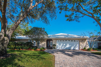 Medium sized and beige contemporary bungalow render house exterior in Tampa with a hip roof.