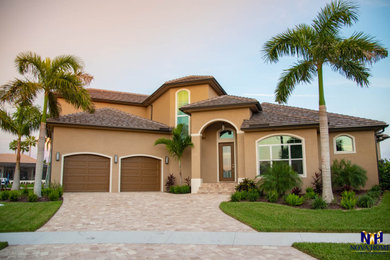 Example of a large beige two-story house exterior design in Miami with a tile roof