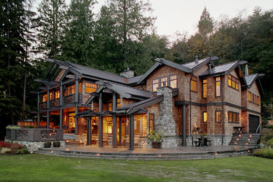 Foto della villa grande marrone american style a due piani con rivestimenti misti, tetto a capanna e copertura in metallo o lamiera