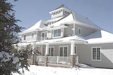 Diseño de fachada de casa gris costera grande de tres plantas con revestimiento de madera, tejado a cuatro aguas y tejado de teja de madera