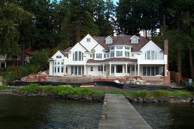 Diseño de fachada blanca clásica extra grande de dos plantas con revestimiento de madera y tejado a dos aguas