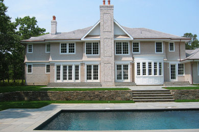Inspiration for a large timeless beige two-story wood exterior home remodel in New York with a hip roof