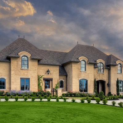 Inspiration for a large timeless beige two-story brick house exterior remodel in Little Rock with a shingle roof