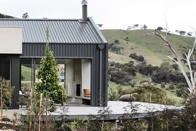 Cette image montre une grande façade de maison design de plain-pied avec un revêtement mixte, un toit à deux pans et un toit en métal.