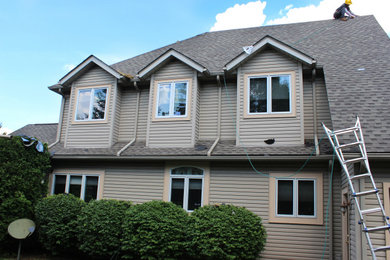 Imagen de fachada de casa beige de dos plantas con tejado de teja de madera