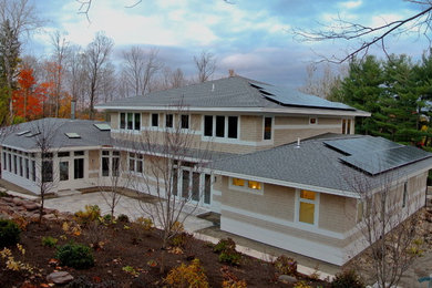 Cette image montre une grande façade de maison beige design en bois à un étage avec un toit à quatre pans.