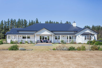 Ejemplo de fachada de casa blanca de estilo de casa de campo extra grande de una planta con revestimientos combinados, tejado a cuatro aguas y tejado de varios materiales