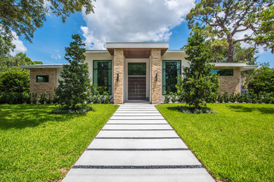 Example of a trendy white one-story stucco house exterior design in Tampa with a metal roof
