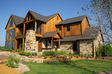 Large rustic two-story stone exterior home idea in Dallas