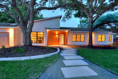 Photo of a white retro bungalow house exterior in Austin with wood cladding and a lean-to roof.