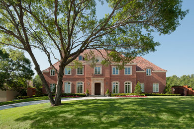 Inspiration for a large timeless red two-story brick exterior home remodel in Dallas with a hip roof