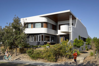 Cette photo montre une façade de maison blanche bord de mer en bois à un étage avec un toit plat.