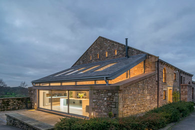 Idée de décoration pour une façade de maison champêtre en pierre à un étage avec un toit à deux pans.