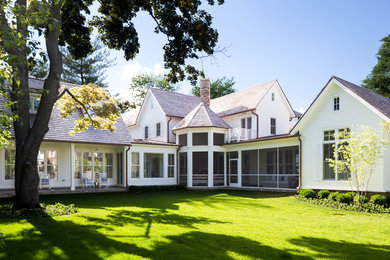 Foto della facciata di una casa bianca classica a due piani di medie dimensioni con rivestimento in legno e falda a timpano