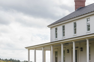 Ejemplo de fachada de casa blanca tradicional grande de dos plantas con revestimiento de madera, tejado a dos aguas y tejado de metal