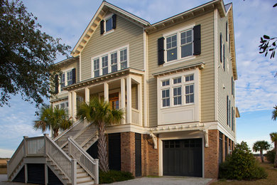 Example of a large beach style beige three-story wood gable roof design in Charleston