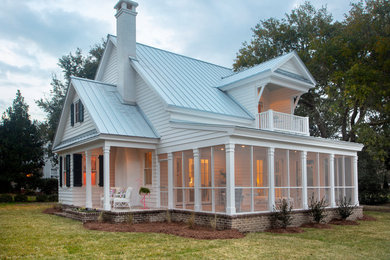 Example of a beach style white two-story exterior home design in New Orleans with a metal roof