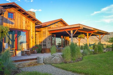 Ejemplo de fachada de casa marrón rústica de tamaño medio de una planta con revestimiento de madera, tejado a dos aguas y tejado de teja de madera