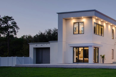 Diseño de fachada de casa blanca minimalista de tamaño medio de dos plantas con revestimiento de estuco y tejado plano