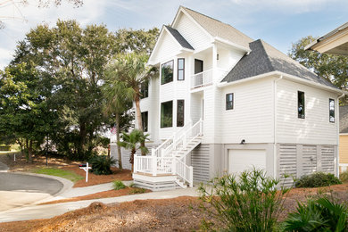Example of a beach style white house exterior design in Charleston with a shingle roof