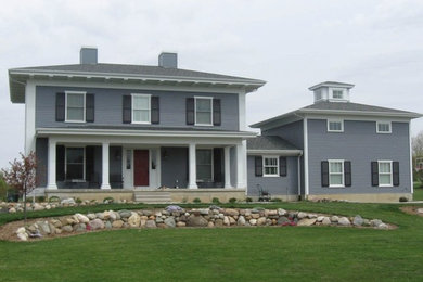 Modelo de fachada de casa azul clásica grande de dos plantas con tejado a cuatro aguas, revestimiento de aglomerado de cemento y tejado de teja de madera