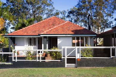 Cette photo montre une façade de maison blanche chic de plain-pied avec un toit à quatre pans et un toit en tuile.