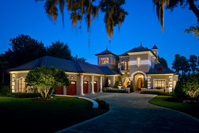 Example of a huge tuscan gray two-story stucco house exterior design in Orlando with a hip roof and a tile roof