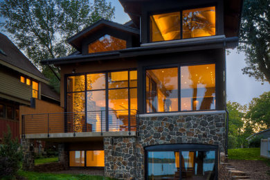 Diseño de fachada de casa beige actual grande de dos plantas con revestimientos combinados, tejado a dos aguas y tejado de teja de madera