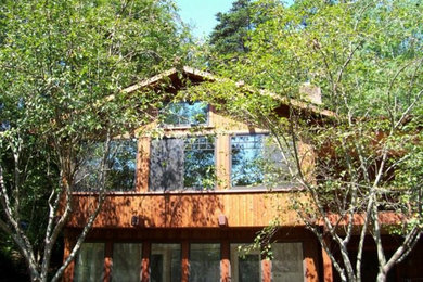 Imagen de fachada marrón de una planta con revestimiento de madera y tejado a dos aguas