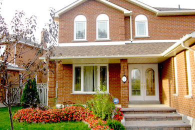 Red brick exterior home photo in Toronto with a hip roof
