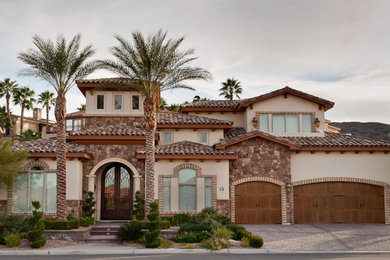 Inspiration for a mid-sized mediterranean beige two-story stone exterior home remodel in Orange County with a clipped gable roof