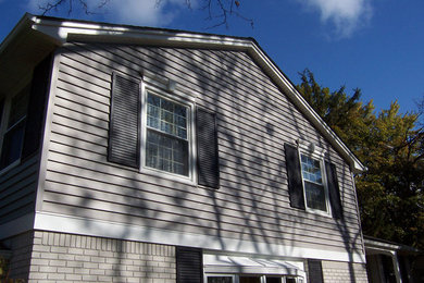 Cette image montre une façade de maison grise de taille moyenne et à un étage avec un revêtement mixte.