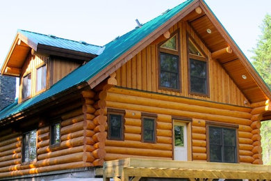 Ejemplo de fachada de casa marrón rústica de tamaño medio de tres plantas con revestimiento de madera, tejado a dos aguas y tejado de metal