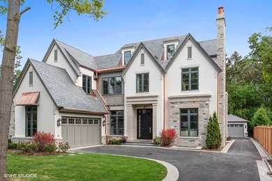 Large transitional gray three-story stone house exterior idea in Chicago with a gambrel roof and a shingle roof