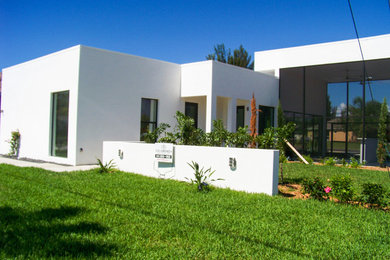 Ejemplo de fachada de casa blanca moderna de tamaño medio de una planta con revestimiento de hormigón, tejado plano y tejado de varios materiales